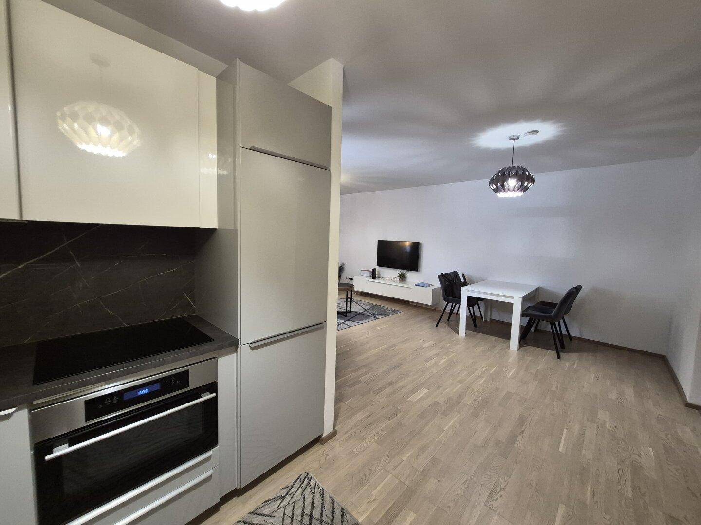 Moderne Küche mit hellen Schränken und Essbereich in einem offenen Wohnkonzept mit Holzboden.