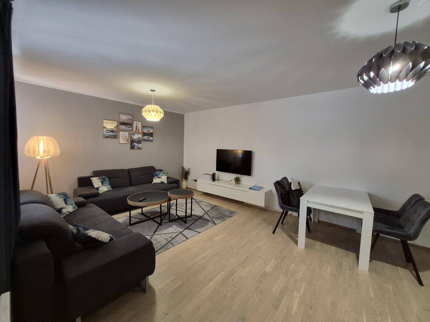 Offener Wohnbereich mit bequemen Sofas, Couchtischen und einem Esstisch im Hintergrund, hell und modern.