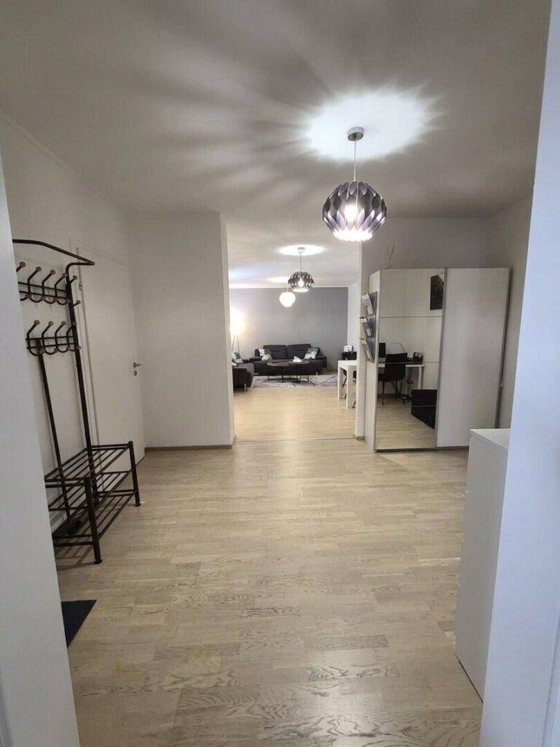 Langer Flur mit Garderobe und Blick auf den offenen Wohnbereich im Hintergrund, hell und geräumig.