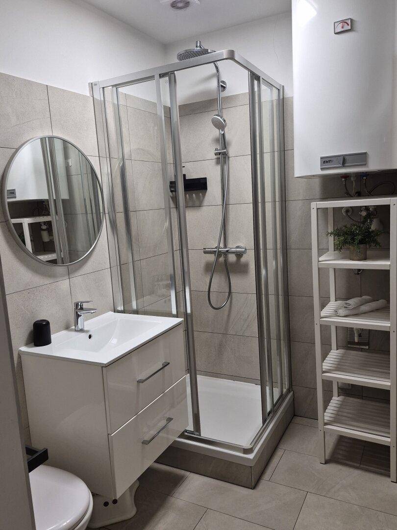 Modernes Badezimmer mit Duschkabine, Waschbeckenunterschrank und hellgrauen Fliesen.