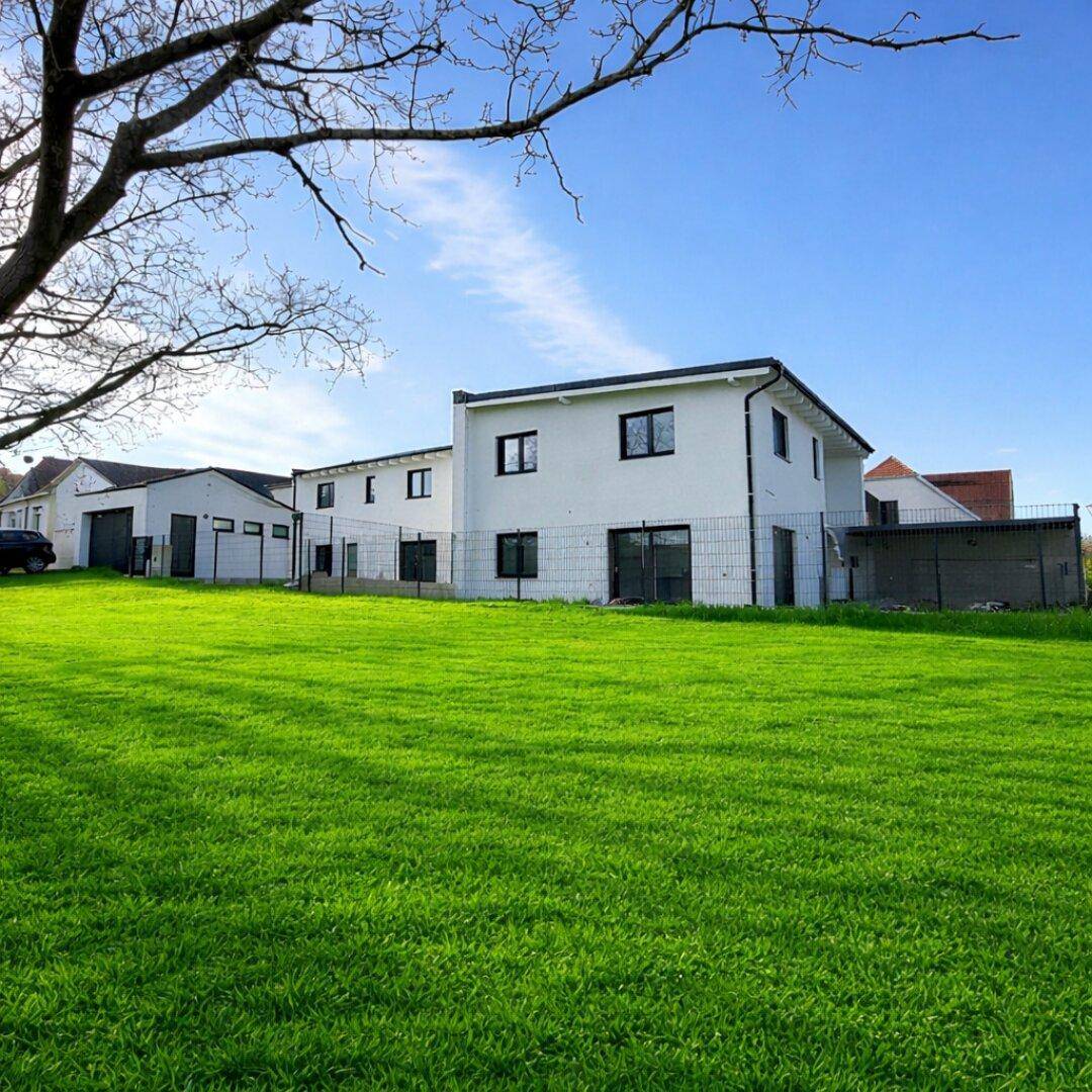 Modernes Einfamilienhaus mit weitläufigem Rasen und sonniger Ausrichtung in ländlicher Umgebung.
