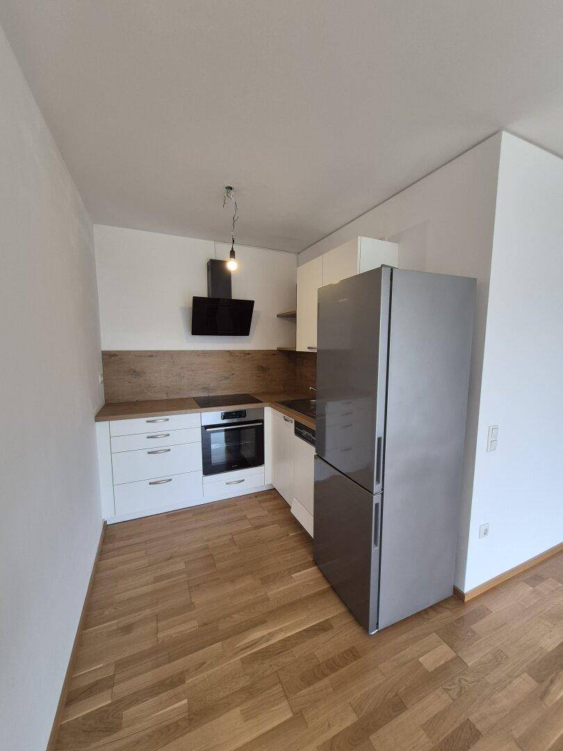 Moderne Einbauküche mit weißen Schränken, Holz-Arbeitsplatte und Edelstahlgeräten.