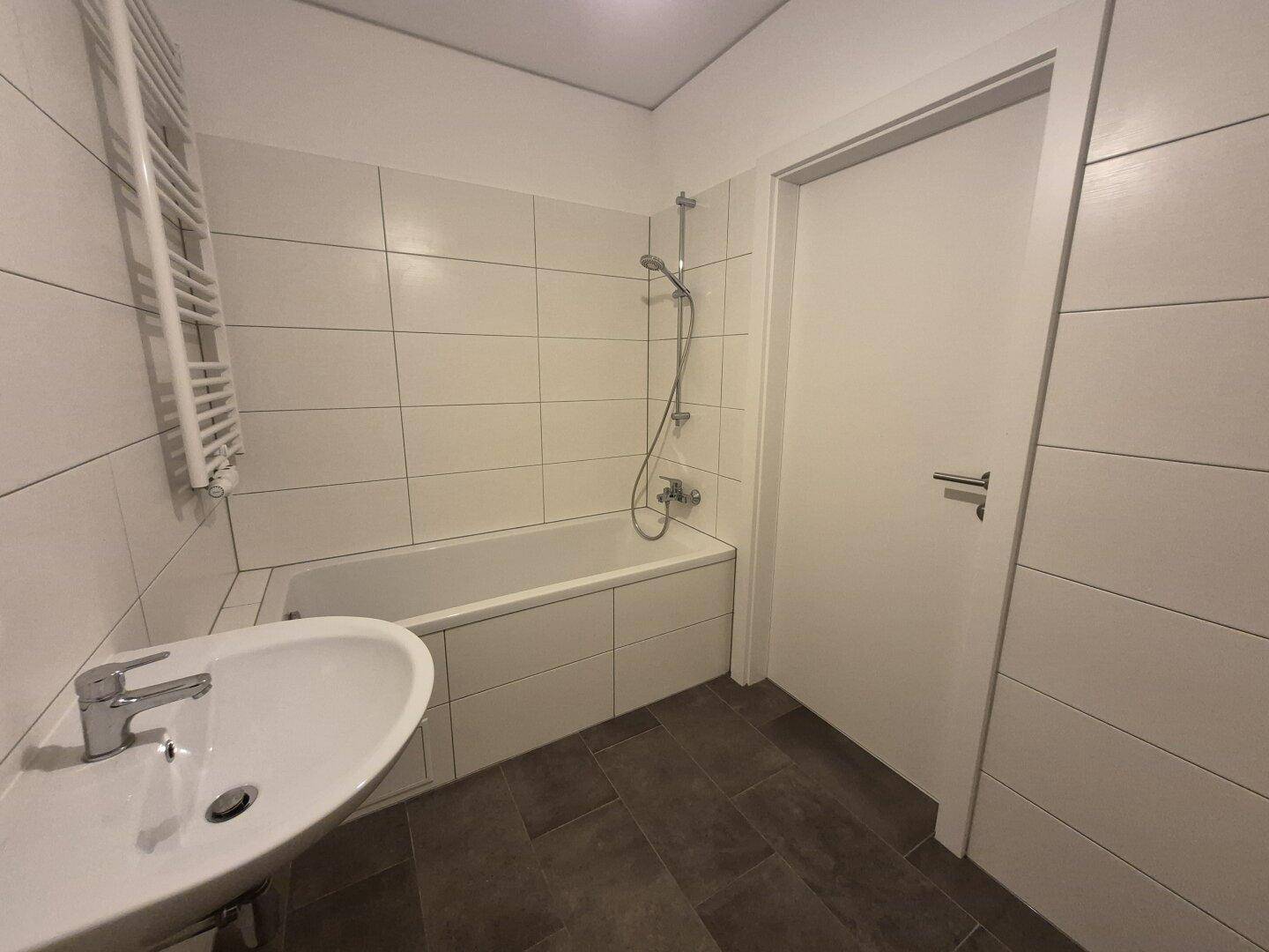 Helles Badezimmer mit Badewanne, Duschfunktion und einem modernen Waschbecken.