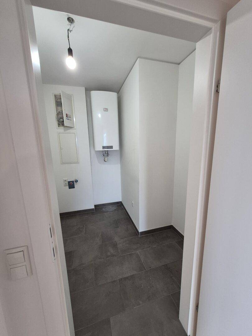 Praktischer Hauswirtschaftsraum mit Fliesenboden und Warmwasserbereiter.