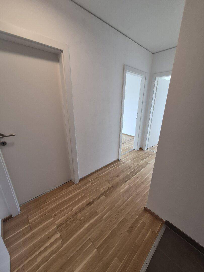 Heller Flur mit Holzparkettboden und weißen Türen, der zu weiteren Räumen führt.