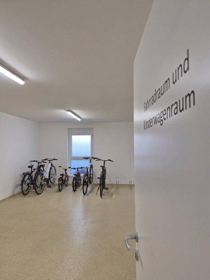 Geräumiger Fahrrad- und Kinderwagenraum mit Fenster und mehreren Fahrrädern.