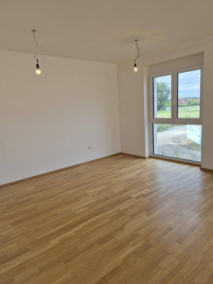 Helles Schlafzimmer mit Parkettboden und großem Fenster, das viel Licht spendet.