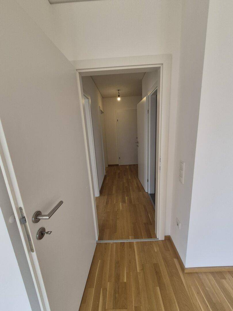Heller Flur mit Parkettboden und weißen Türen, der zu weiteren Räumen führt.