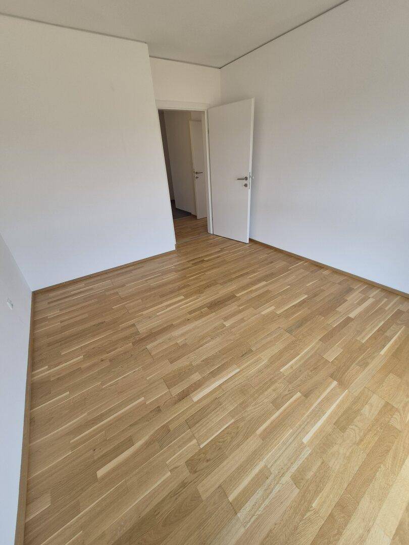 Unmöbliertes Zimmer mit Parkettboden und weiß gestrichenen Wänden, bereit zur Gestaltung.