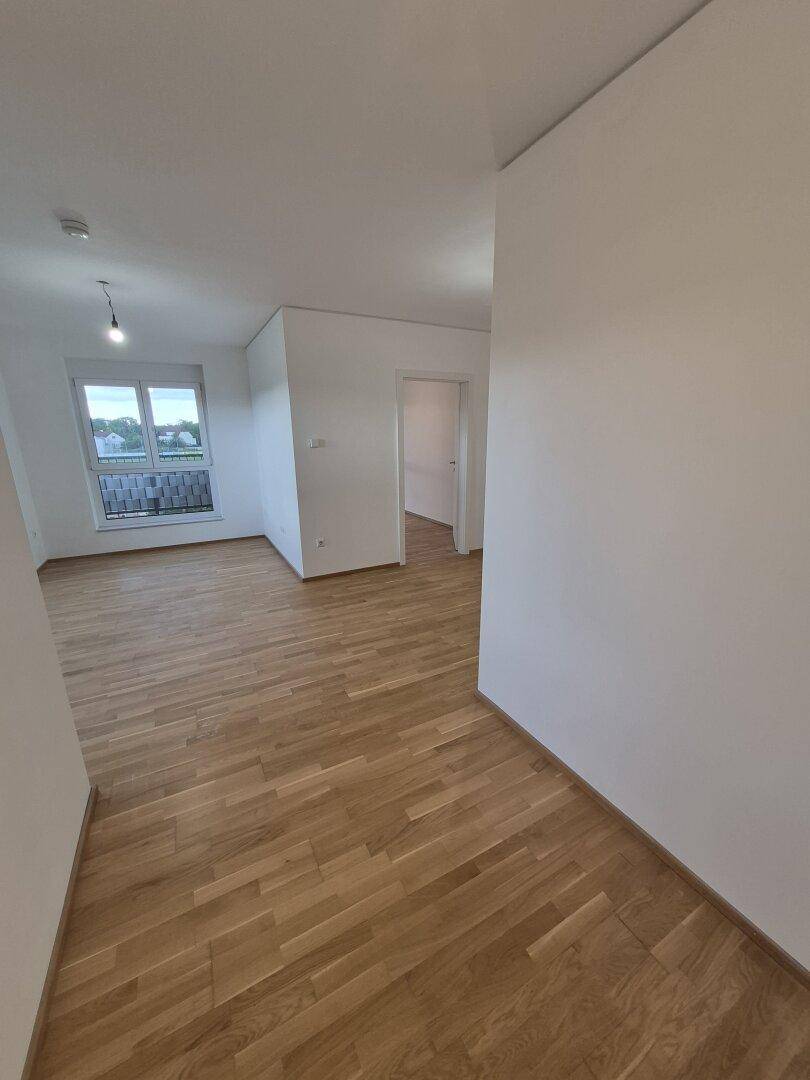Geräumiger Wohnbereich mit Parkettboden und Zugang zu weiteren Zimmern, hell und einladend.