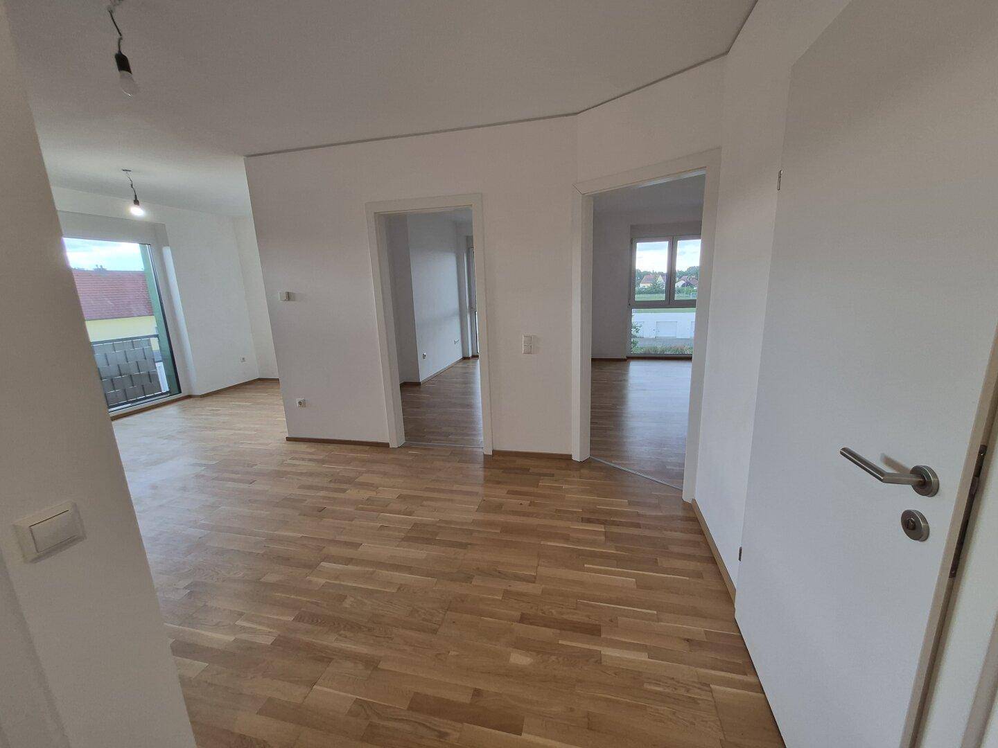 Heller Wohnbereich mit Parkettboden und Zugang zu weiteren Zimmern, ideal für offenes Wohnen.