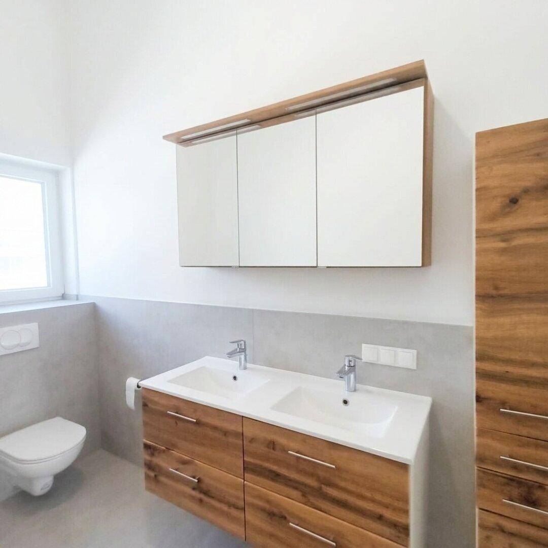 Doppelwaschbecken mit Holzunterschrank und Spiegelschrank in einem modernen Badezimmer.