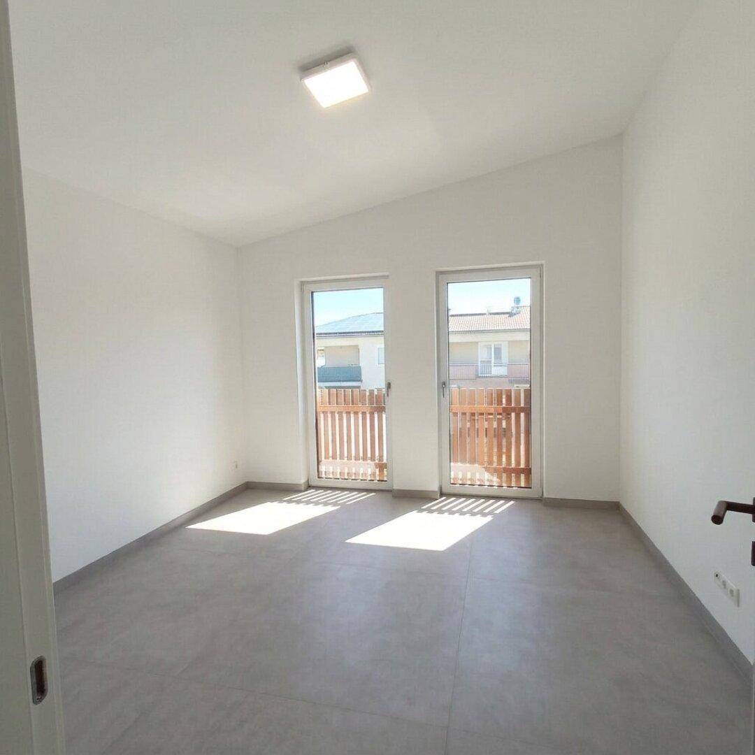 Helles Schlafzimmer mit Zugang zu einem Balkon und schrägen Decken, ideal für natürliches Licht.