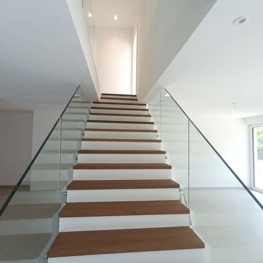 Moderne Treppe mit Holzstufen und Glasgeländer, die die verschiedenen Ebenen verbindet.