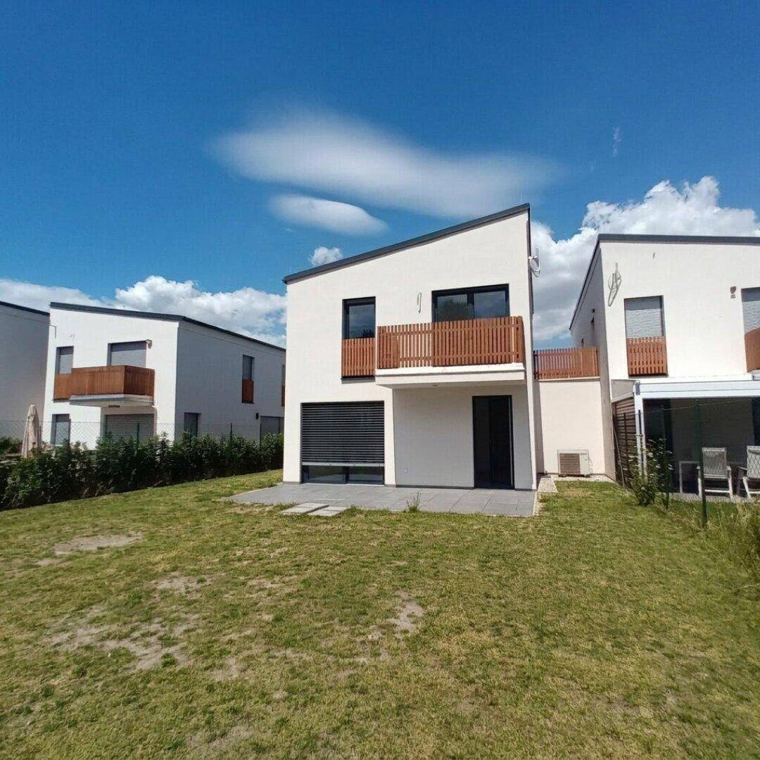 Rückansicht eines modernen Hauses mit Terrasse und Gartenbereich.