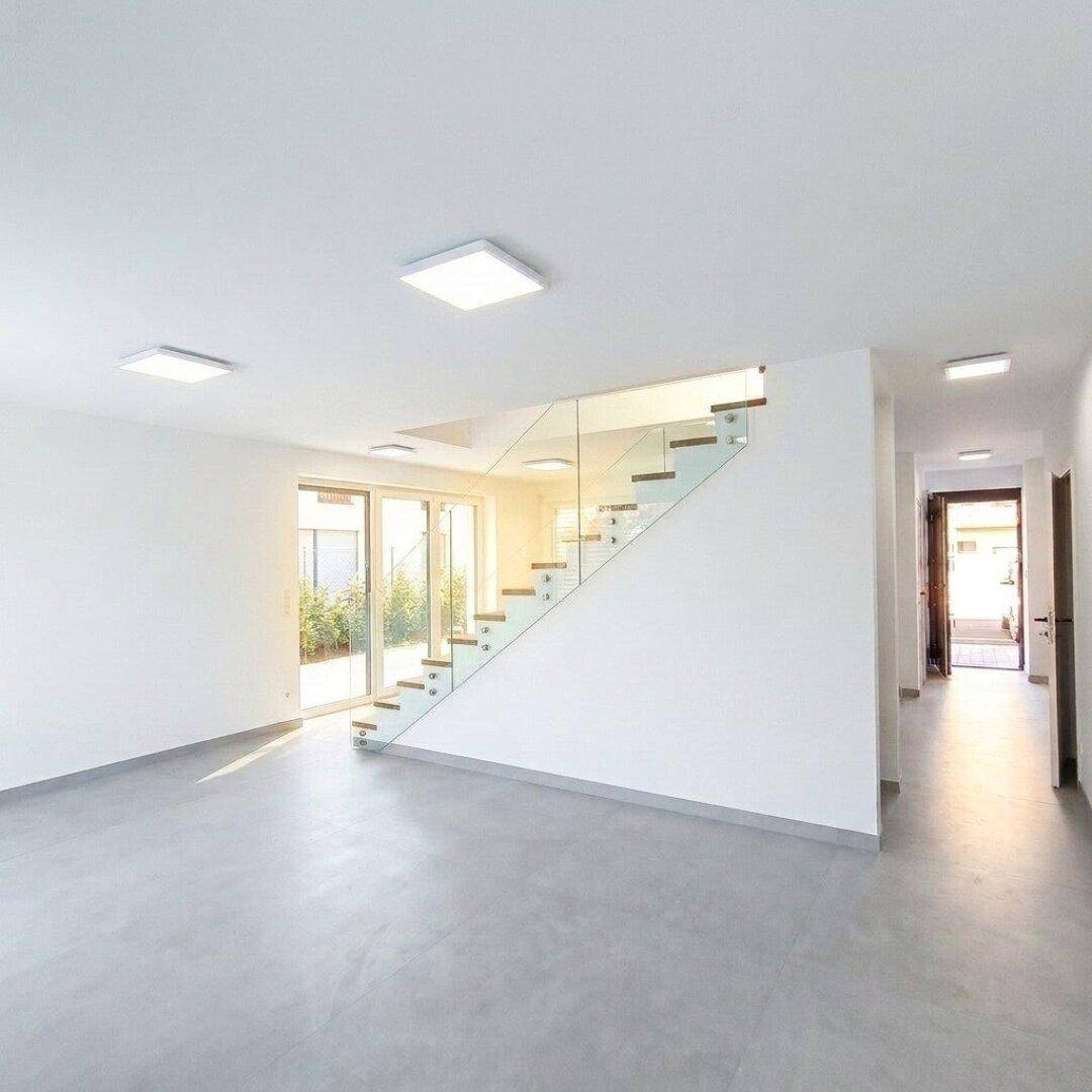 Offener Wohnbereich mit moderner Treppe und Zugang zu einer sonnigen Terrasse.