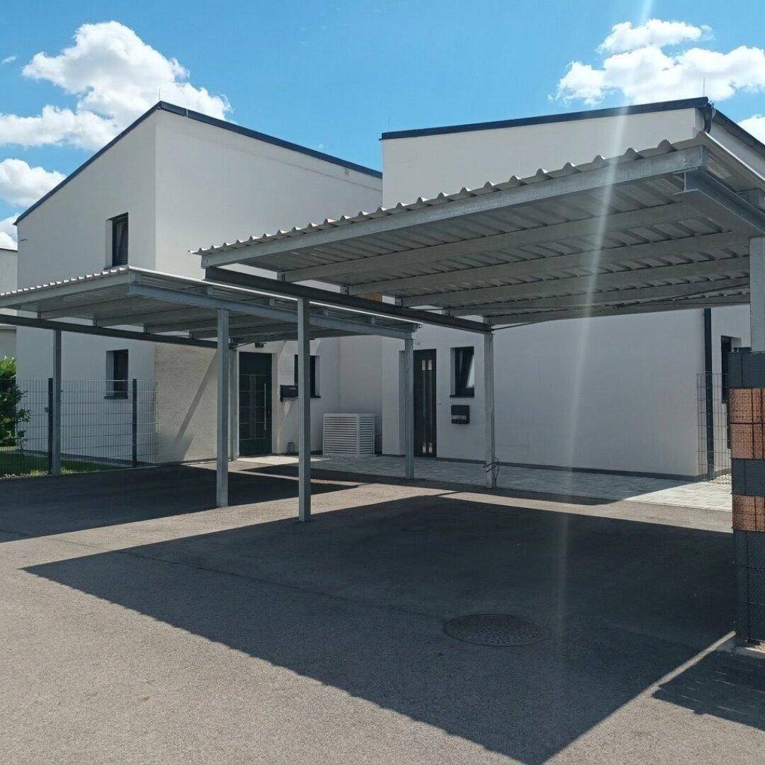 Überdachte Carports bieten Parkmöglichkeiten neben den modernen Wohnhäusern.