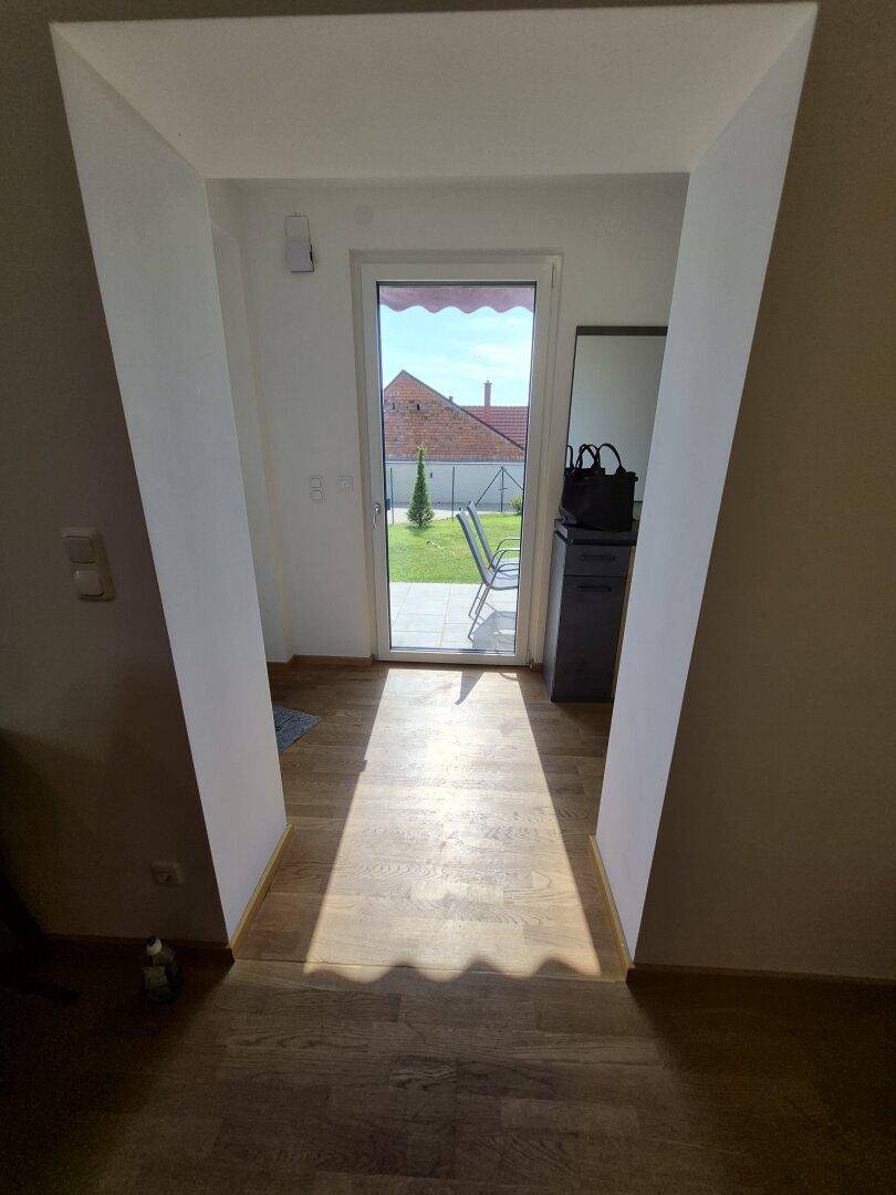 Heller Flur mit Holzboden und direktem Zugang zu einem sonnigen Außenbereich.