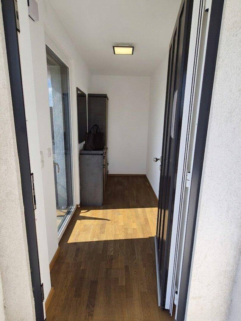 Heller Eingangsbereich mit Holzboden und Zugang zu einem Außenbereich.