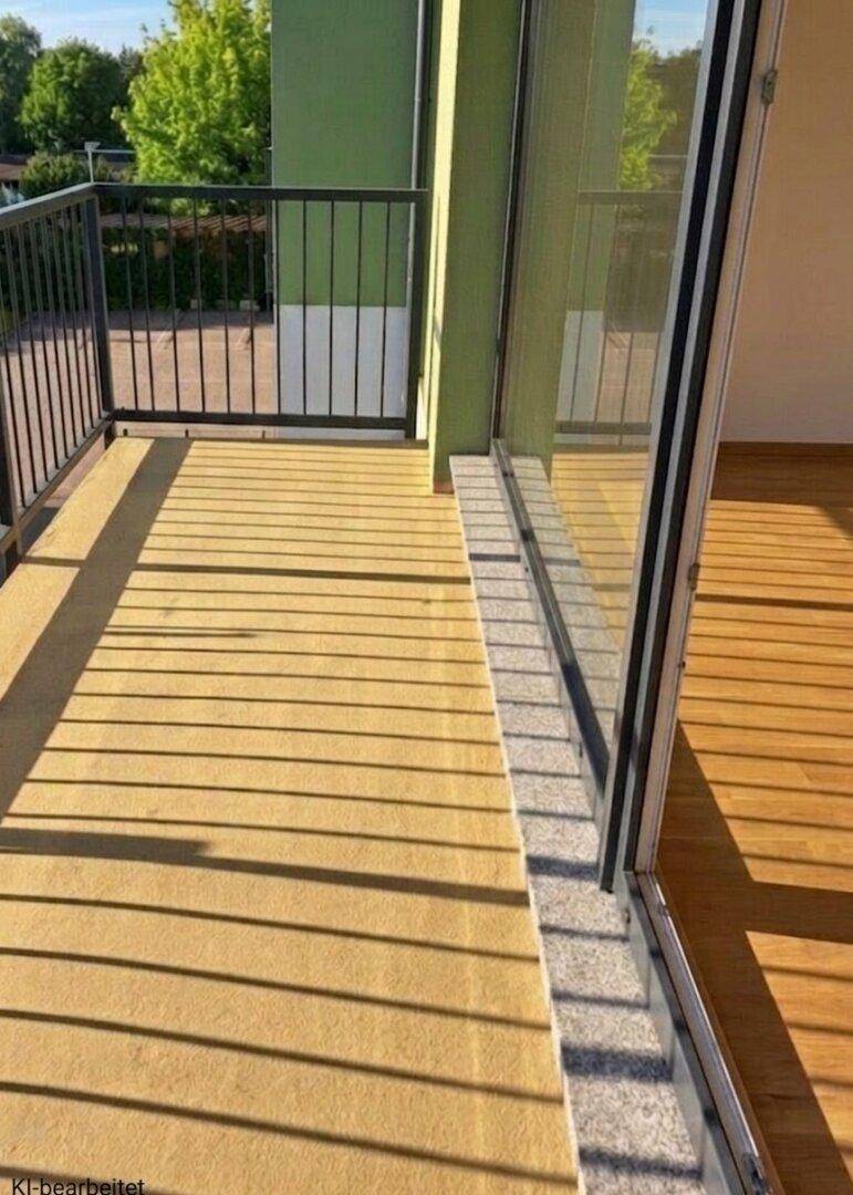 Sonniger Balkon mit beigem Boden und schwarzem Geländer, verbunden mit dem Innenbereich.