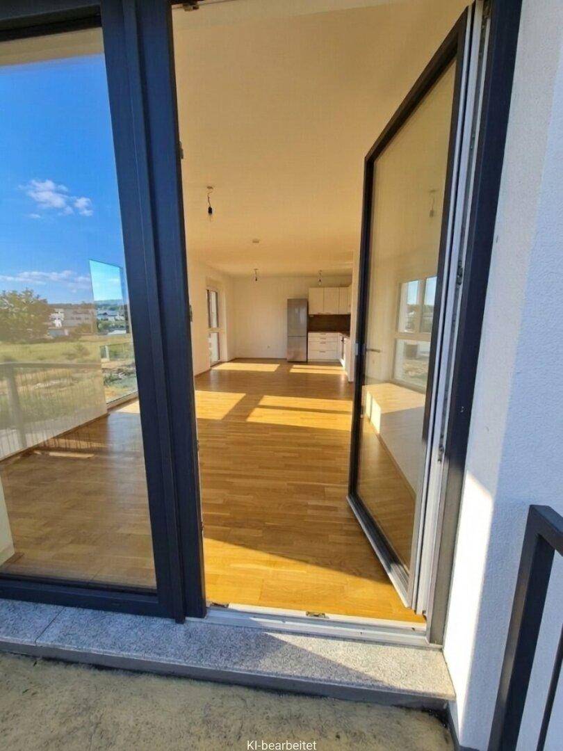 Heller, offener Wohnbereich mit Holzboden und Blick auf die Küche von der Terrasse.