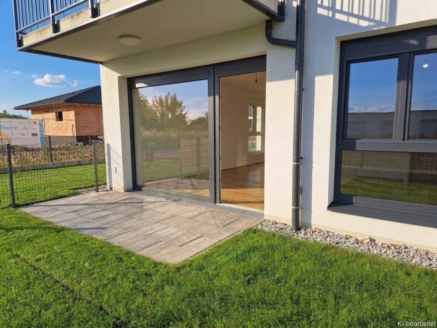 Gepflasterte Terrasse mit Zugang zum Innenbereich und Blick auf den Garten.