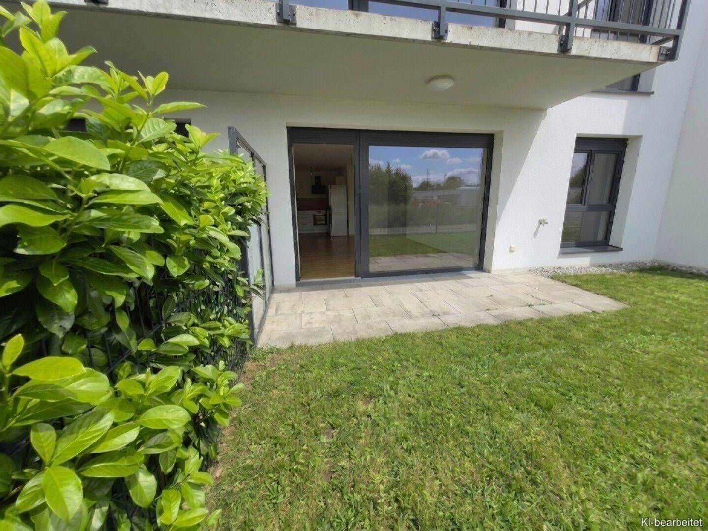 Gepflegter Gartenbereich mit grüner Hecke und direktem Zugang zur Wohnung über eine Terrasse.