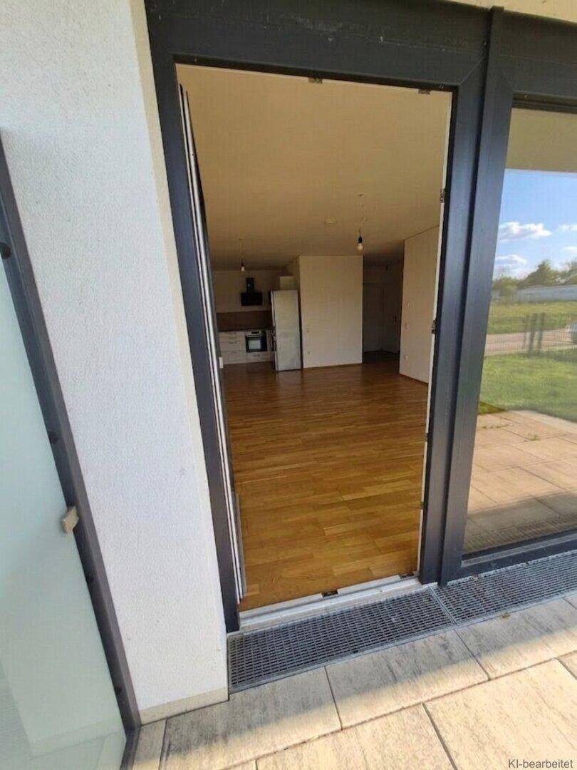 Heller Innenraum mit Holzboden und Blick auf den offenen Wohnbereich mit integrierter Küche.