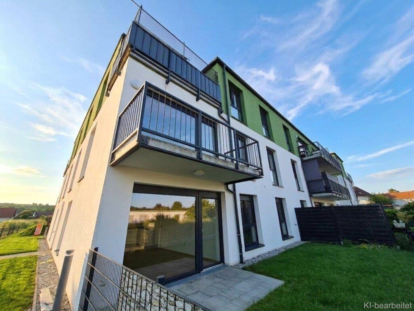 Moderne Wohnanlage mit weißer und grüner Fassade, Balkonen und großzügigen Fensterfronten.