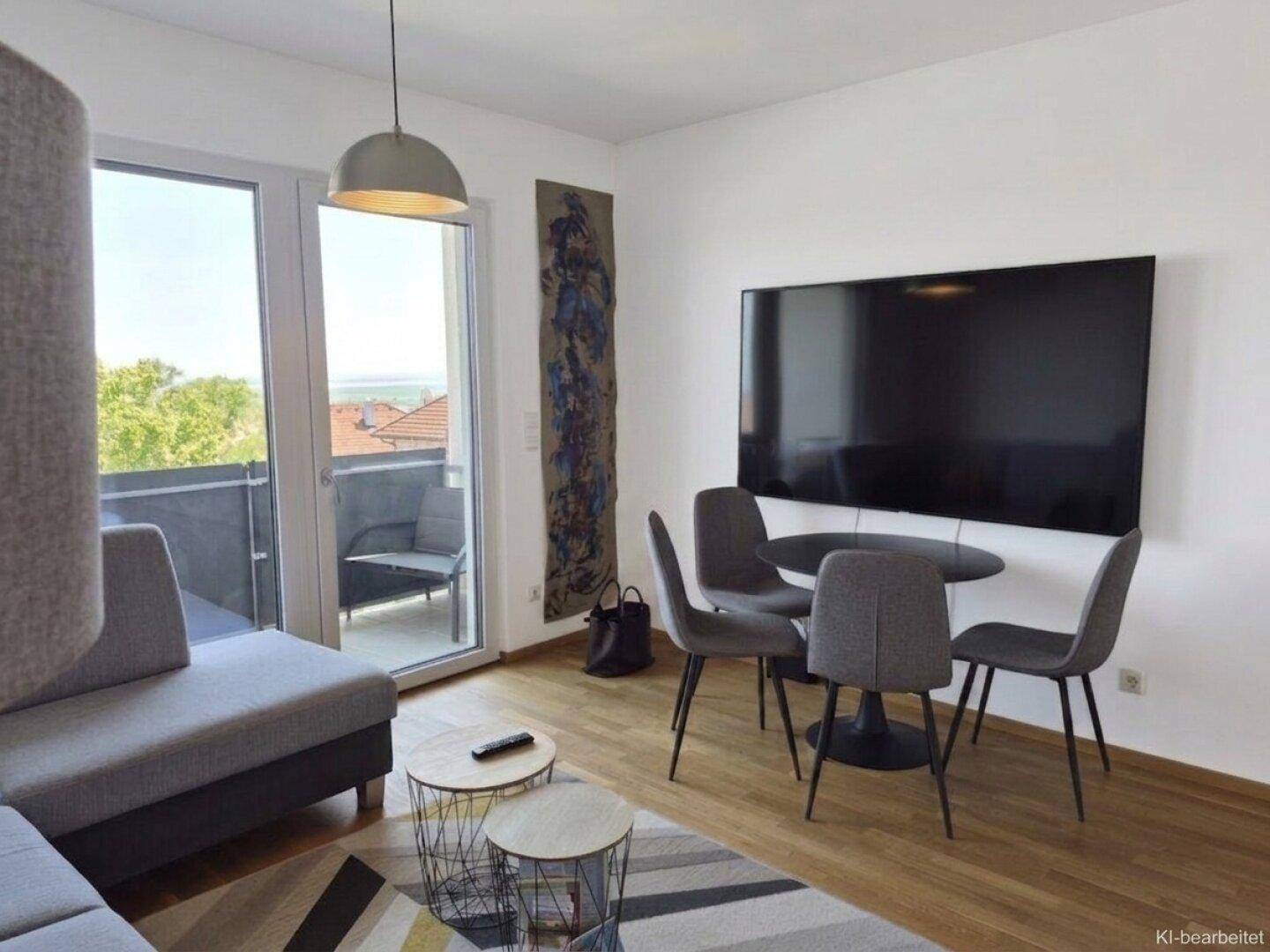 Wohn- und Essbereich mit großem Fernseher und Zugang zum möblierten Balkon.
