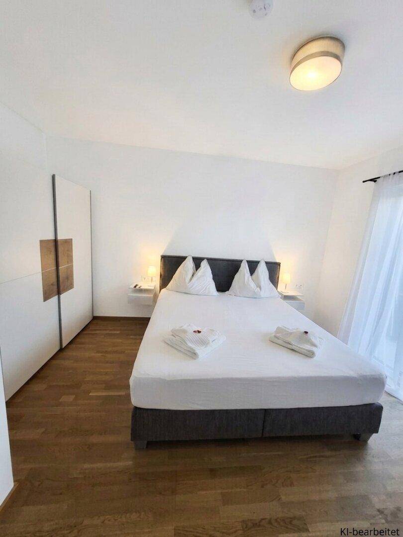 Helles Schlafzimmer mit Holzboden, Doppelbett, Nachttischen und einem großen Kleiderschrank.