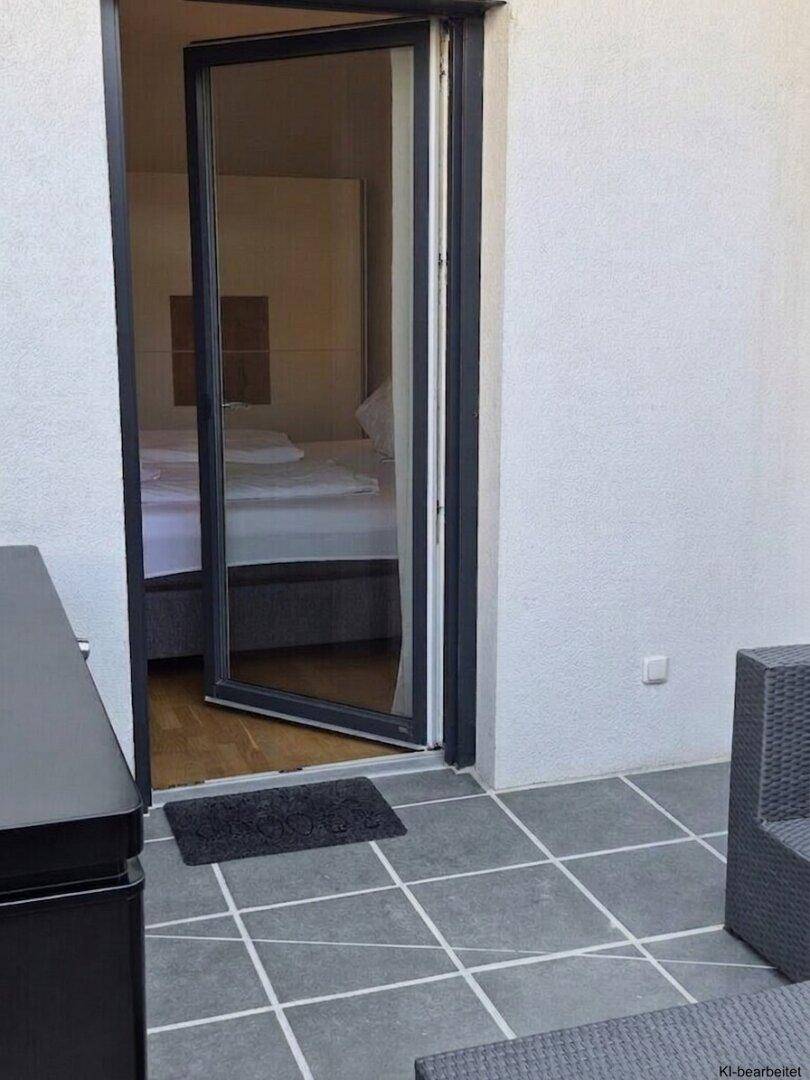 Geflieste Terrasse mit Zugang zu einem Schlafzimmer, ideal für frische Luft am Morgen.