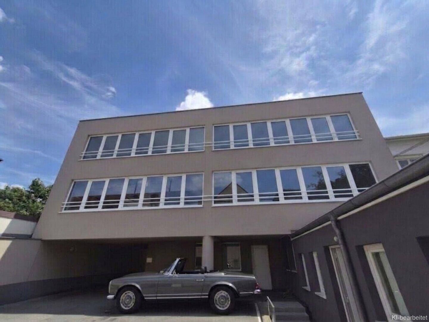 Moderne Gebäudefassade mit großen Fensterfronten und integriertem Carport im Erdgeschoss.