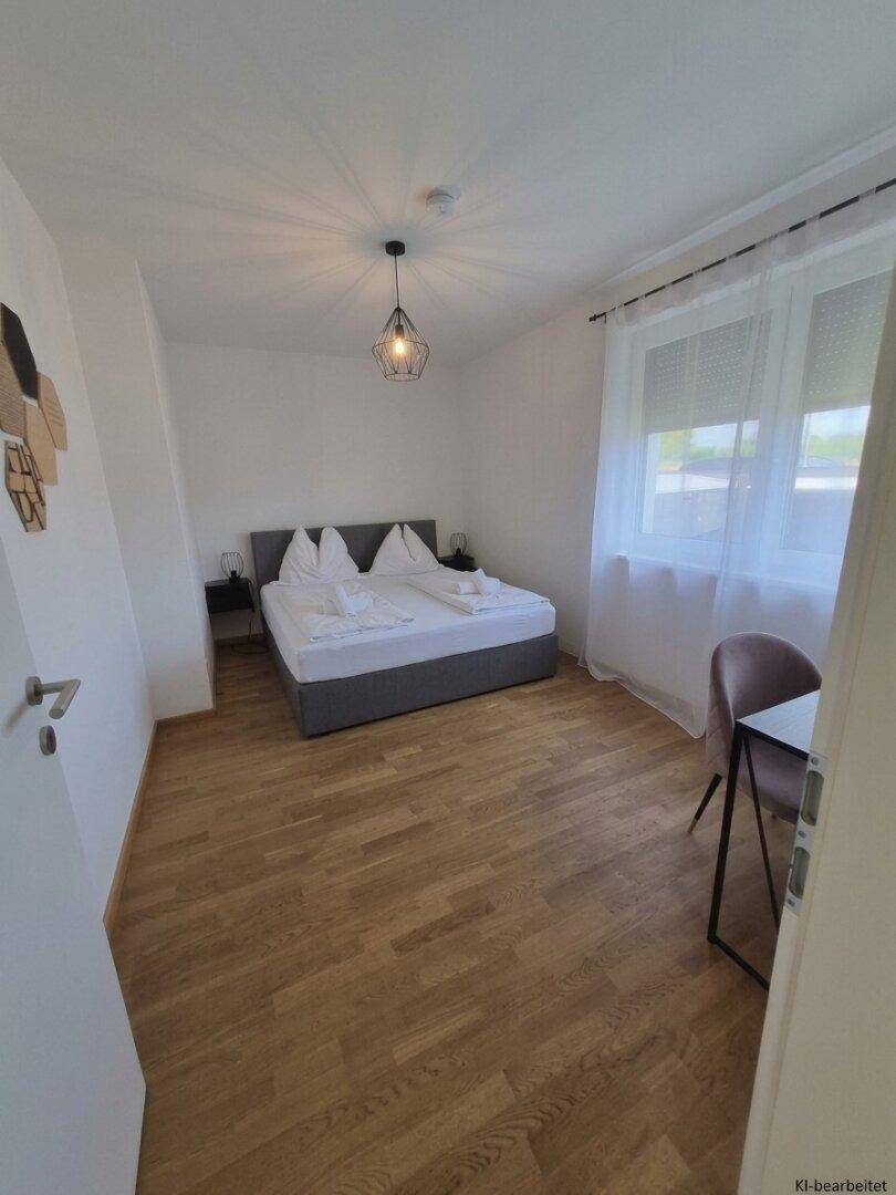 Geräumiges Schlafzimmer mit Doppelbett, Schreibtisch und großem Fenster für viel Tageslicht.