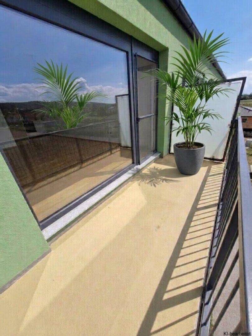 Heller Balkon mit Topfpflanze und großer Glasfront, die den Innenraum mit Tageslicht versorgt.