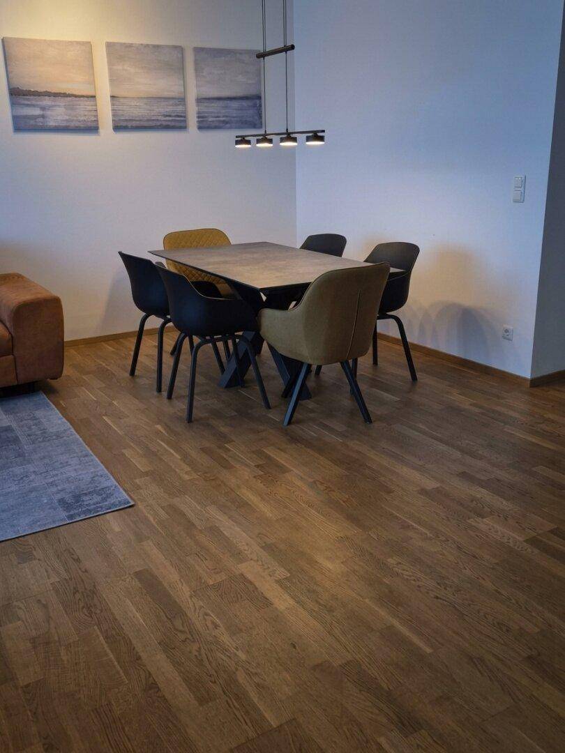 Heller Essbereich mit modernem Esstisch, bequemen Stühlen und Holzboden.