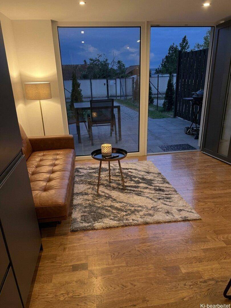 Gemütliches Wohnzimmer mit Ledersofa und Zugang zu einer kleinen Terrasse am Abend.