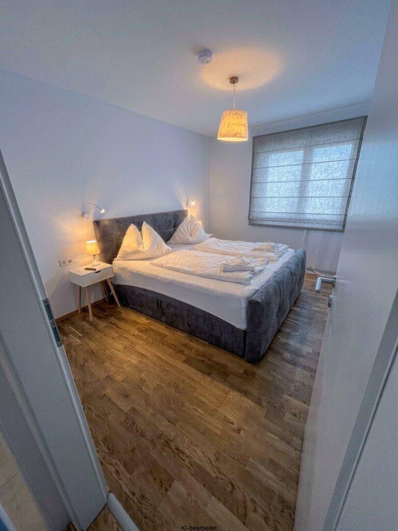 Gemütliches Schlafzimmer mit großem Doppelbett, Nachttischen und Holzboden.