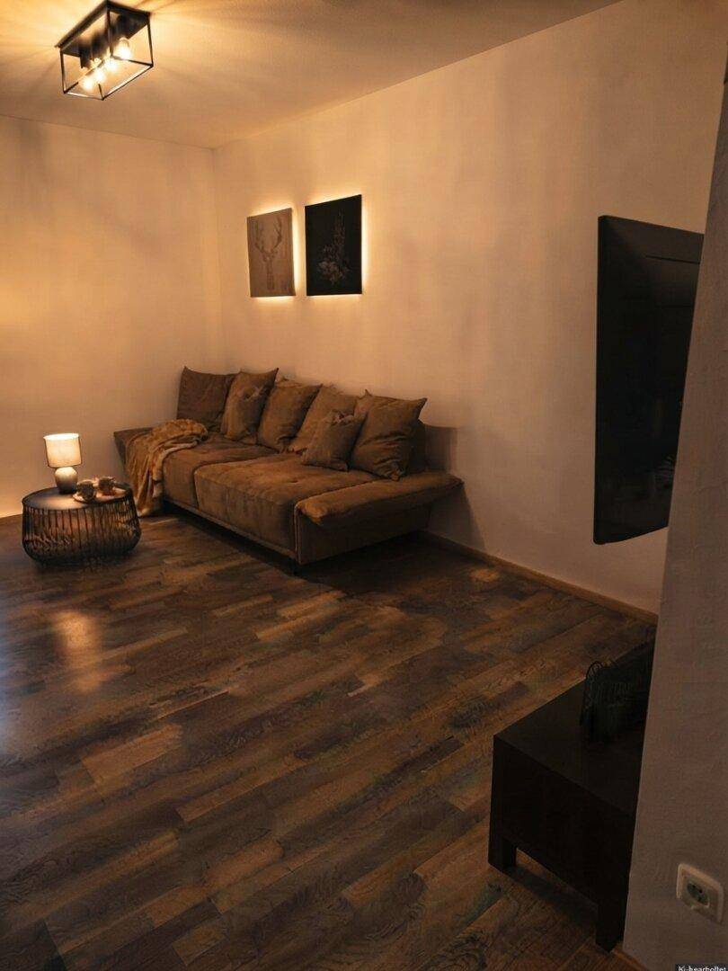 Gemütlicher Wohnbereich mit braunem Sofa, Holzboden und indirekter Beleuchtung.