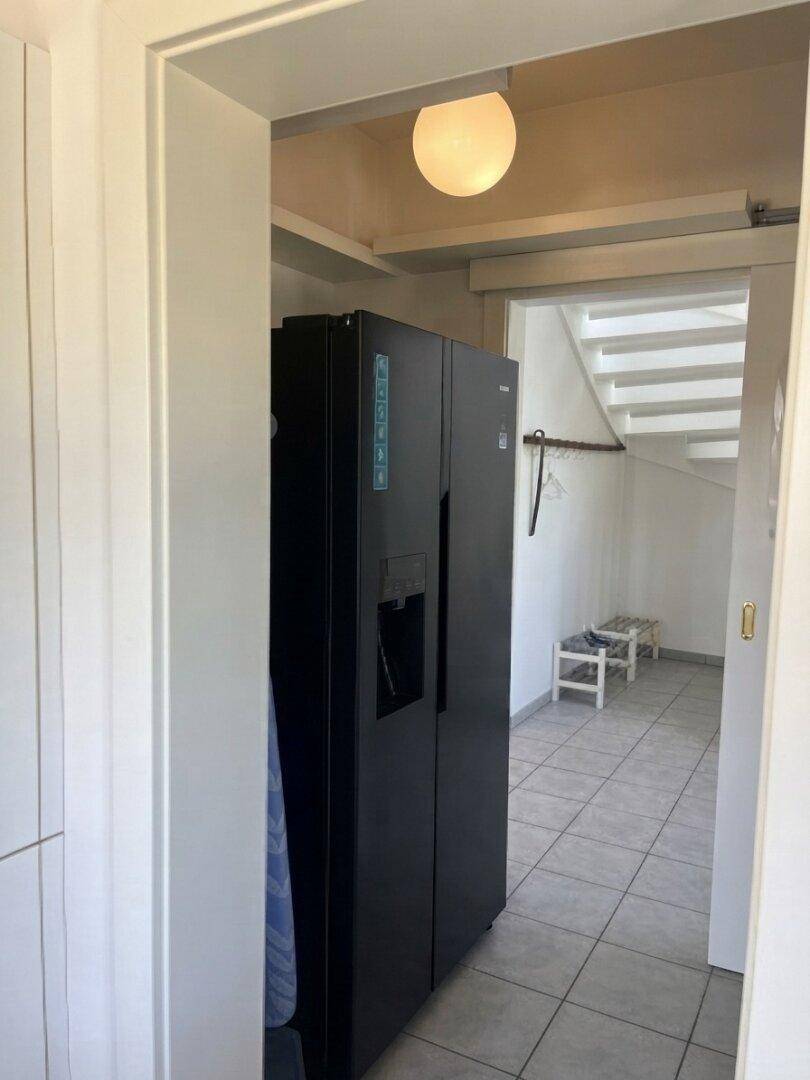 Geräumiger Flur mit großem Kühlschrank und Treppenaufgang zum Obergeschoss.
