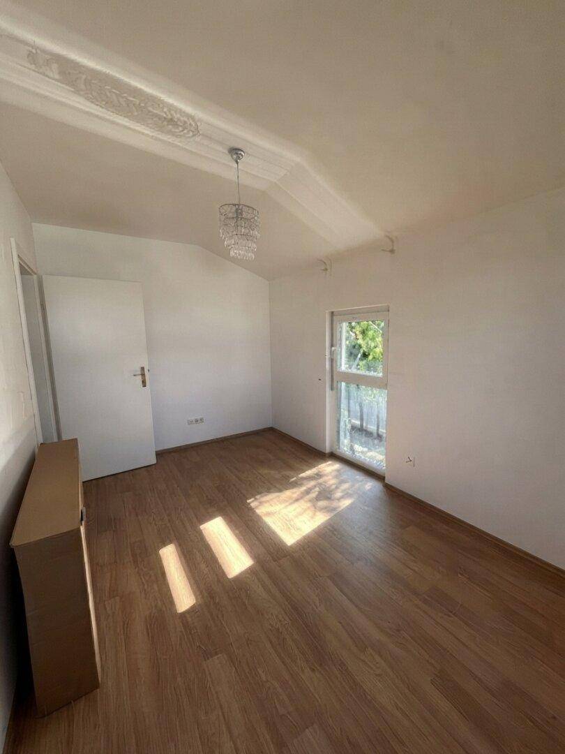 Helles Zimmer mit Holzboden und Zugang zum Außenbereich, ideal für ein Schlafzimmer.
