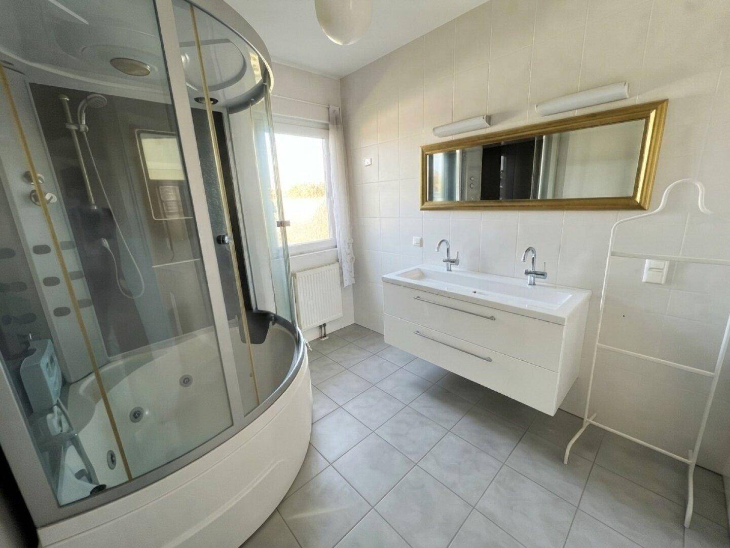 Geräumiges Badezimmer mit Doppelwaschbecken, großem Spiegel und Dusch-Whirlpool-Kabine.