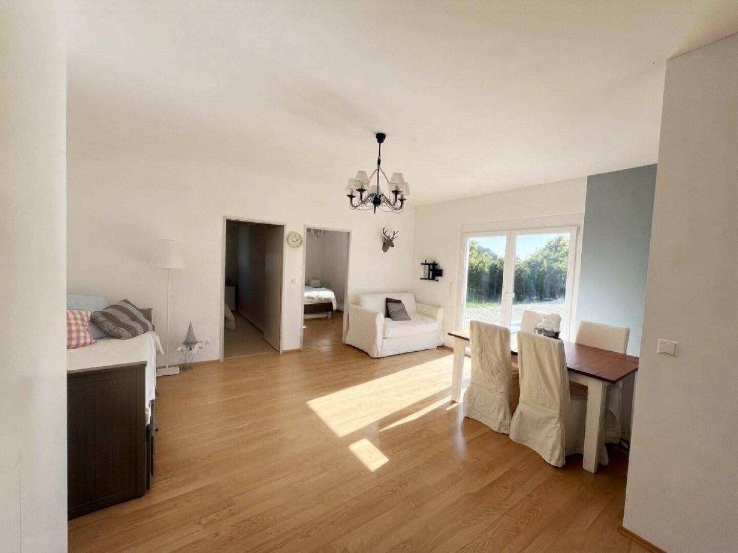 Geräumiger Wohn-Essbereich mit Holzboden, Esstisch und Zugang zum Außenbereich.