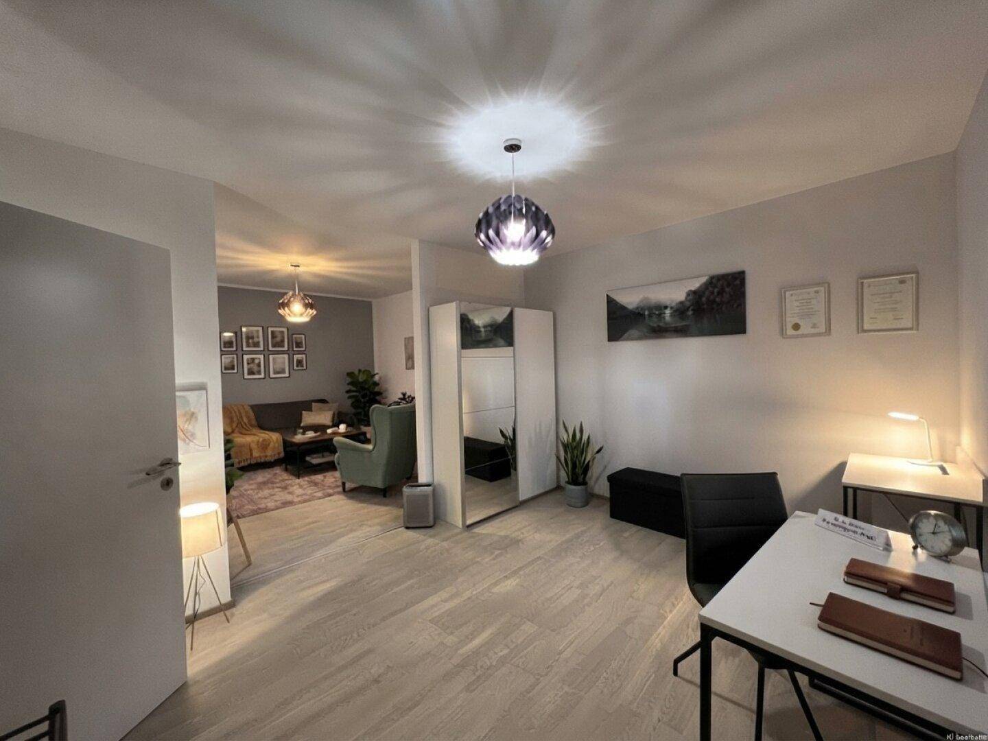 Helles Arbeitszimmer mit Schreibtisch und Stauraum, das in einen gemütlichen Wohnbereich übergeht.