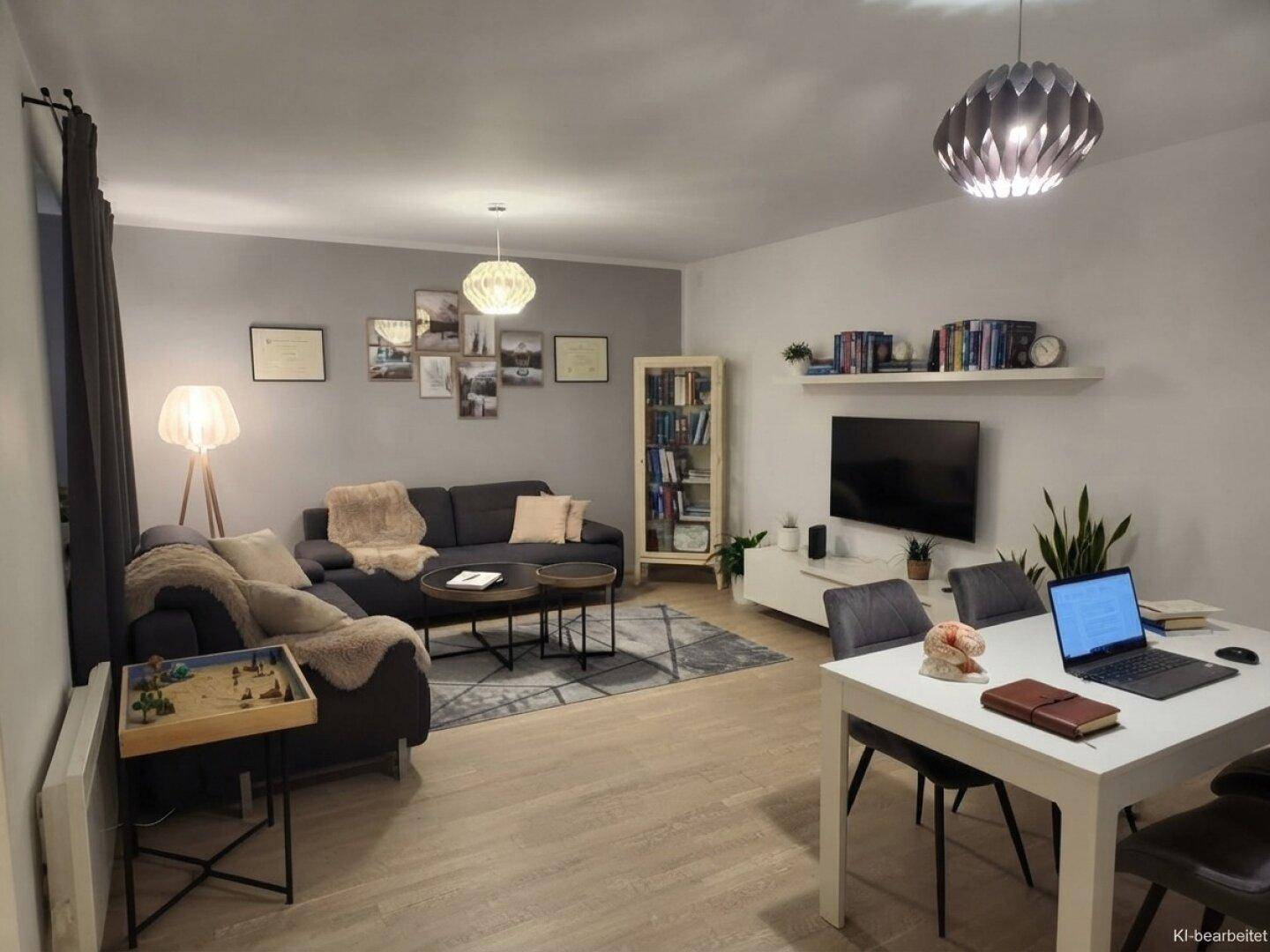 Moderner Wohnbereich mit großem Sofa, Fernseher und einem Esstisch, der auch als Arbeitsplatz dient.