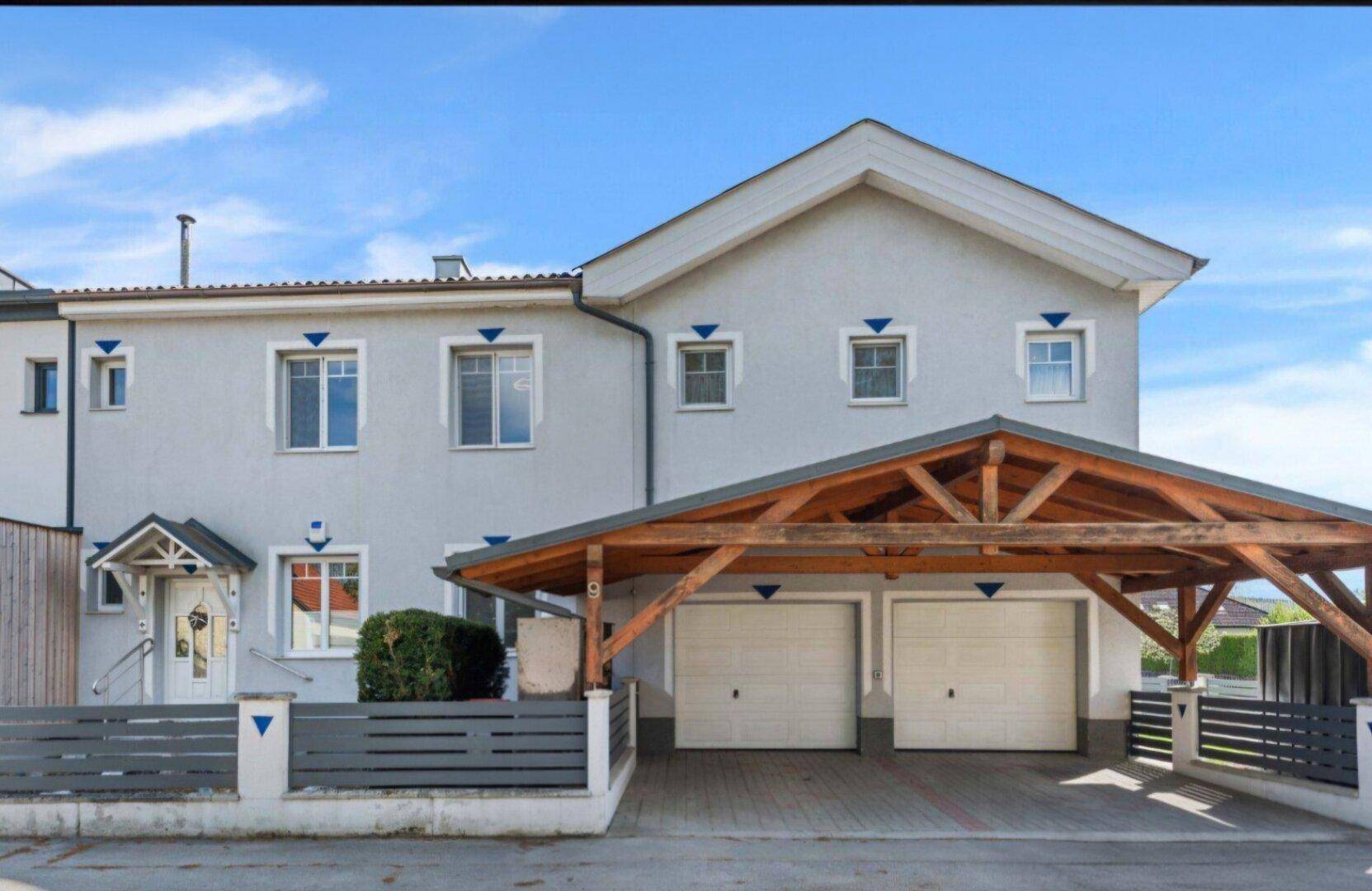 Vorderansicht des Hauses mit Doppelcarport und Garagenzugang.