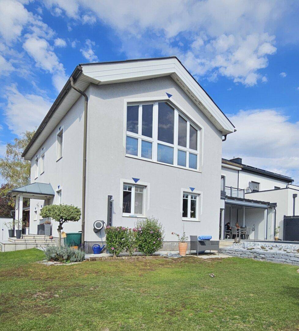 Seitenansicht des Hauses mit gepflegtem Garten und großen Fenstern im Giebelbereich.