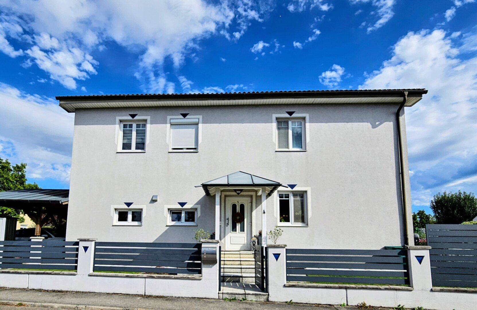 Frontansicht des Hauses mit einladendem Eingangsbereich und moderner Zaunanlage.