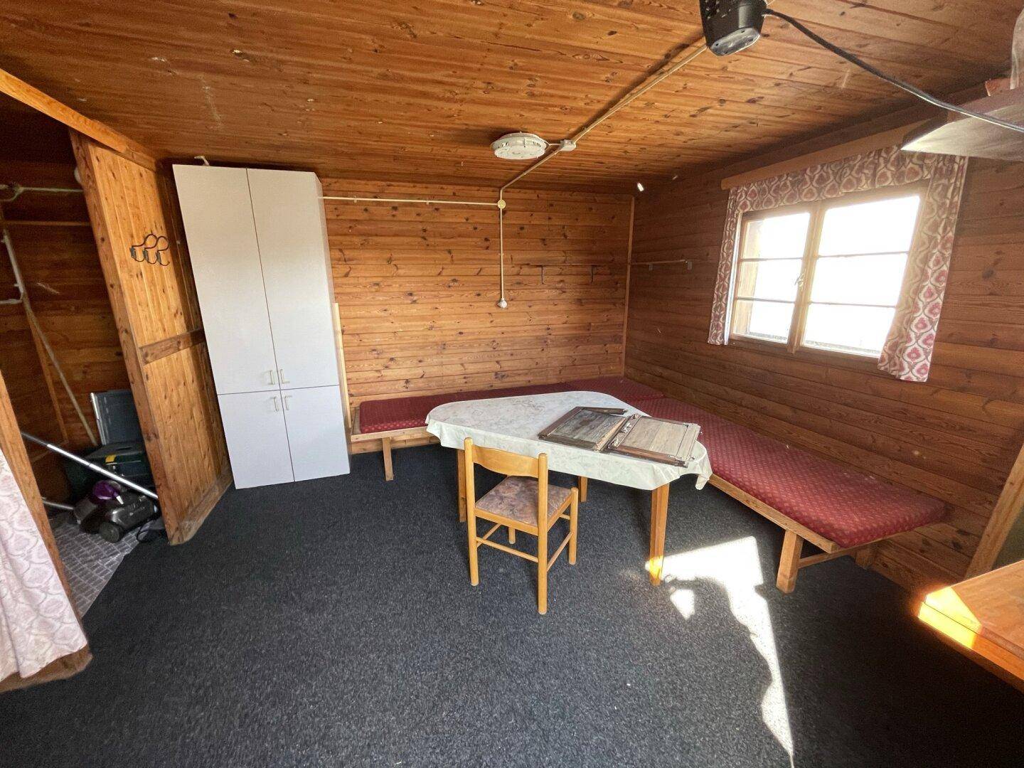 Rustikaler Wohnraum mit Holzvertäfelung, Sitzbänken und kleinem Esstisch.