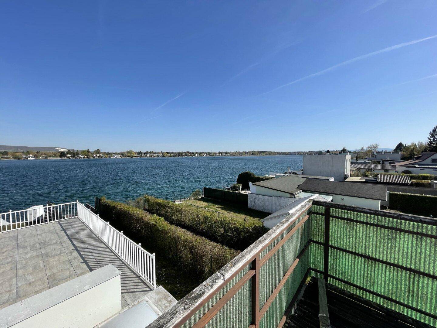 Große geflieste Terrasse mit Geländer und weitem Blick über den See.